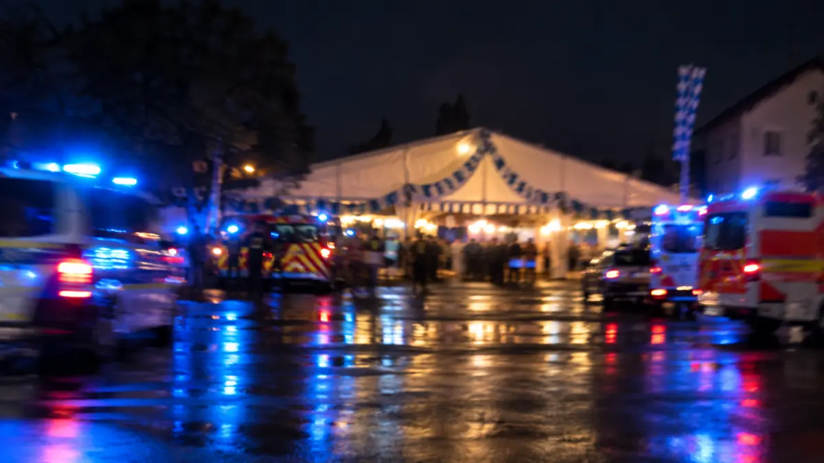 Unscharfes Festzelt bei Nacht mit Blaulicht und Einsatzfahrzeugen