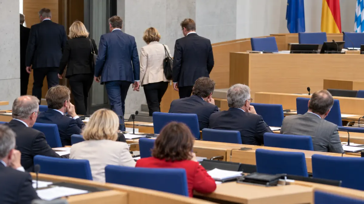 Mehrere Abgeordnete gehen in einem Landtagsplenum Richtung Ausgang, während andere im Saal sitzen