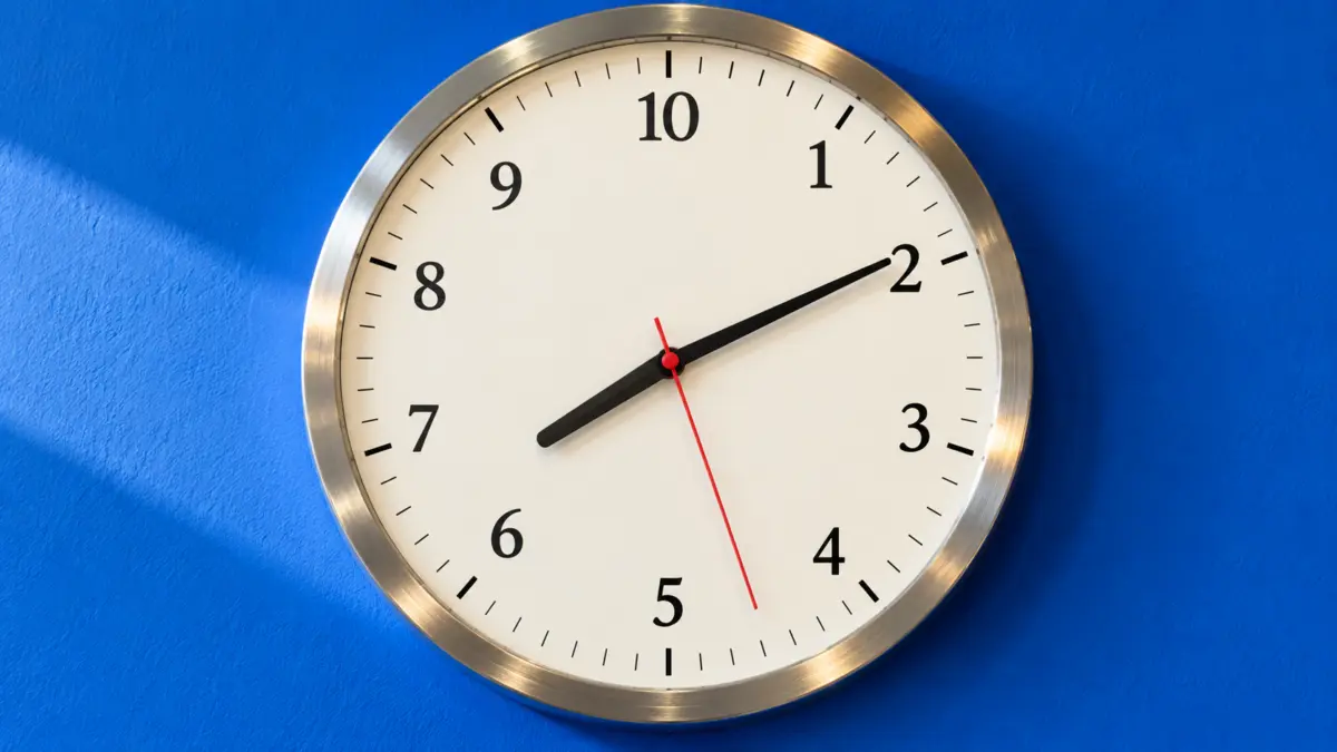 Wanduhr mit zehn statt zwölf Stunden auf dem Zifferblatt vor blauer Wand