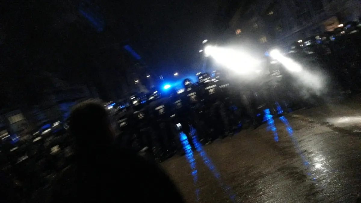 Symbolbild: Polizeikette bei einer nächtlichen Demonstration, Gegenlicht und Blaulicht