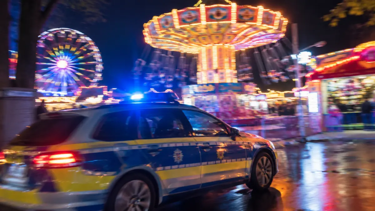Unscharfe Kirmeslichter bei Nacht und ein Polizeiwagen mit Blaulicht